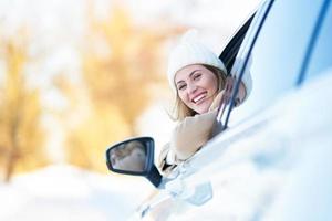 mujer feliz conduciendo un coche en invierno cubierto de nieve foto