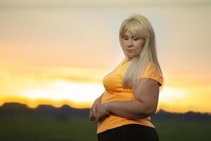 retrato de una mujer europea de mediana edad en chándal, posando para la cámara, relajándose. emocionada mujer con sobrepeso en chándal de moda descansando después de hacer ejercicio. foto