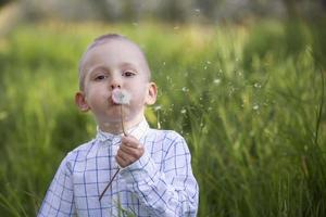 A little boy blows on a dandelion. Future generation. Windmills. Renewable energy sources and sustainable resources - windmills. The child plays and discovers green energy. Wind turbine. Environment photo