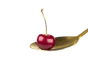 Cherry berries on a golden spoon. Close-up on a white background of wild cherries. Beautiful year. photo