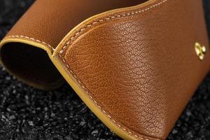 Part of a brown leather wallet or case with stitching. photo