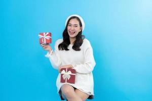 Happy woman on blue background. She is excited for Christmas. wearing a white coat and hat Waiting to celebrate the New Year's Ready to give a special gift for everyone in the new year 2023 in coming photo