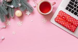 Office work table with Cristmas and New Year decoration top view, flat lay on pink background. Copy space for text during winter holidays photo