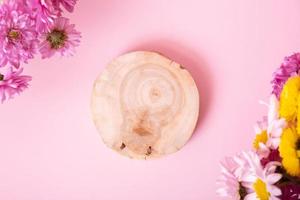 Wooden podium or pedestal with chrysanthemum flowers top view. Mockup for your cosmetic products flat lay photo