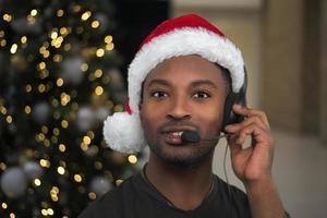 centro de apoyo de vacaciones asistente de servicio al cliente de la línea de ayuda de navidad con sombrero rojo de santa claus y micrófono con auriculares foto