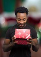 hombre abriendo caja de regalo roja mirando dentro sorpresa de navidad expresión emocionada foto