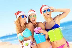 grupo de chicas con sombreros de santa divirtiéndose en la playa foto