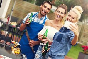 grupo de amigos haciendo barbacoa y tomando selfie foto