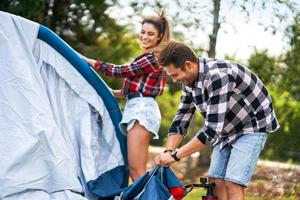 Young nice couple having fun on camping setting up tent photo