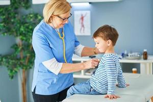 Pediatrician doctor examining little kids in clinic photo