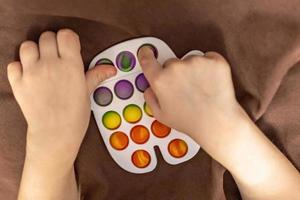 pop it es un juguete antiestrés multicolor en las manos de los niños. juego de burbujas juguetes antiestrés. foto