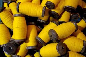 large grup yellow yarn on wood spool, yarn on tube, a collection of yellow threads on spool, which will be fabricated. yellow string. yellow thread. photo