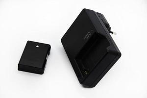cargador negro y batería para cámaras. cargador y batería sobre un fondo blanco. accesorios negros para la cámara. foto