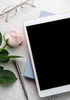 Bouquet of roses and tablet  on concrete background. photo