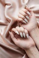 Hands of a young woman with white manicure on nails photo