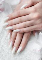 manos de una mujer joven con manicura blanca en las uñas foto