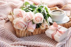 Tray with  bouquet of beautiful pink roses and gift box on  bed.