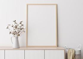 Empty vertical picture frame on white wall in modern living room. Mock up interior in minimalist, scandinavian style. Free space for picture. Console, rattan basket, cotton plant in vase. 3D rendering photo