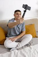 Young man, blogger recording lifestyle blog, talking to camera of smartphone on tripod. Young influencer filming vlog for his channel. Man makes video for his followers online. photo