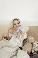 niño enfermo con inhalador para el tratamiento de la tos. niño enfermo inhalando en su cama. temporada de gripe. procedimiento médico en el hogar. interior y ropa en colores tierra naturales. ambiente acogedor. foto