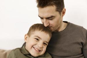 Portrait of father and son. Dad loves his boy. Positive family relationship. Young attractive man and his little kid spending time together. Respect and support, be a good example. Father's Day. photo