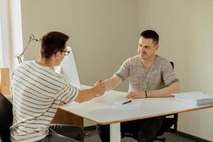 trato exitoso proceso de apretón de manos de dos hombres de negocios. bienvenido a nuestro equipo. gerente joven y serio en el cargo estrechándole la mano a un solicitante de empleo después de una entrevista. apretón de manos de sociedad comercial. foto