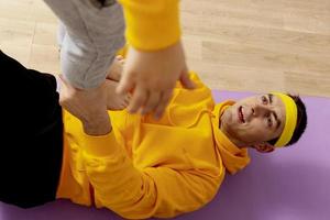 Young man with little boy doing fitness exercises at home. Father and son having fun during sport. Dad and his child making training. Sport, yoga. Workout in the apartment. Healthy lifestyle, family. photo