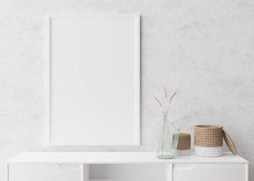 Empty vertical picture frame on white wall in modern living room. Mock up interior in minimalist, scandinavian style. Free space for picture. Console, rattan basket, dried grass in vase. 3D rendering. photo