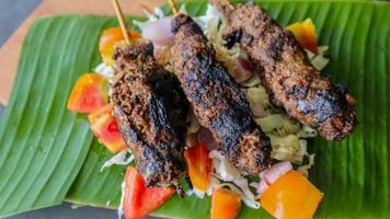 sate buntel or satay buntel is satay made from minced mutton wrapped in mutton fat and then grilled. seasoning with tomatoes, shallots, pepper, cabbage photo