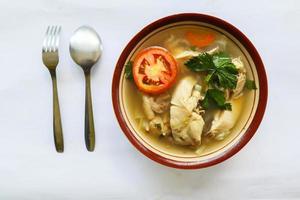 Chicken soup served with vegetables, tomatoes, celery in a bowl, spoon and fork. with black background photo
