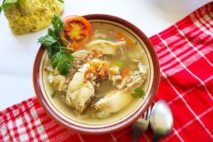 Chicken soup served with vegetables, tomatoes, celery in a bowl, spoon and fork. with black background photo