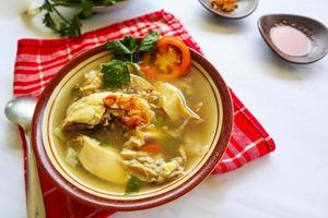 Chicken soup served with vegetables, tomatoes, celery in a bowl, spoon and fork. with black background photo