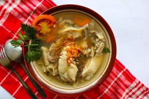 Chicken soup served with vegetables, tomatoes, celery in a bowl, spoon and fork. with black background photo