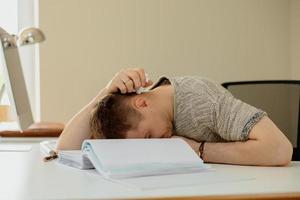 hombre caucásico deprimido con dolor de cabeza sentado en su escritorio en la oficina. El joven empleado estresado tiene problemas en el trabajo. el empresario tiene agotamiento. salud mental. abrumado por el trabajo. plazo, estrés. foto