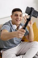 Young man, blogger recording lifestyle blog, talking to camera of smartphone on tripod. Young influencer filming vlog for his channel. Man makes video for his followers online. photo