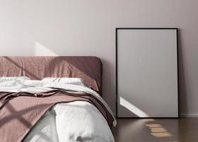Empty vertical picture frame standing on wooden floor in modern bedroom. Mock up interior in minimalist, contemporary style. Free space for picture or poster. Bed, sunlight. 3D rendering. photo