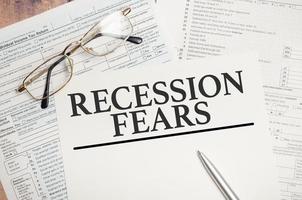 Recession fears symbol. Words on white paper with tax forms photo