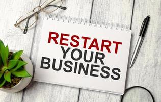 restart your business words on notebook with pen and glasses photo