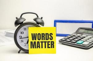 words matter words on yellow sticker with clock, calculator and paper folder photo