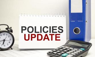 policies update words on white notebook with clock, calculator and paper folder photo