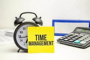 time management words on yellow sticker with clock, calculator and paper folder photo