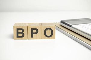 Three wooden cubes with the letters BPO on the bright surface of a grey table. photo