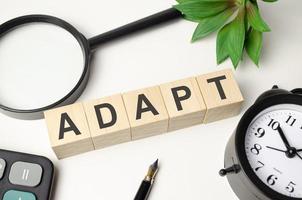 adapt word made with wooden blocks and office supplies photo