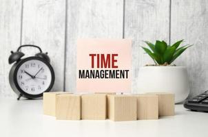 time management on pink sticker with wooden block and alarm clock photo