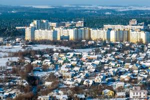 panoramic aerial view of a winter city with a private sector and high-rise residential areas with snow photo