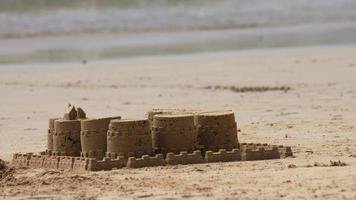 château de sable fait main sur le fond de la vague de la mer video