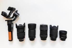 Top view of work space videographer with digital gear, gimbal stabilizer, lens and camera accessory on white table background photo