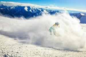 Professional skier at full speed ski downhill on fresh snow do carving in ski resort while training for competition in ski resort with mountains background photo