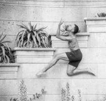 Young dancer positioned against a planter in an atheletic pose photo