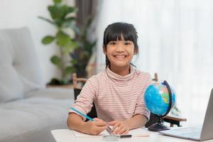 Asian little girl is learning the globe model, concept of save the world and learn through play activity for kid education at home. photo